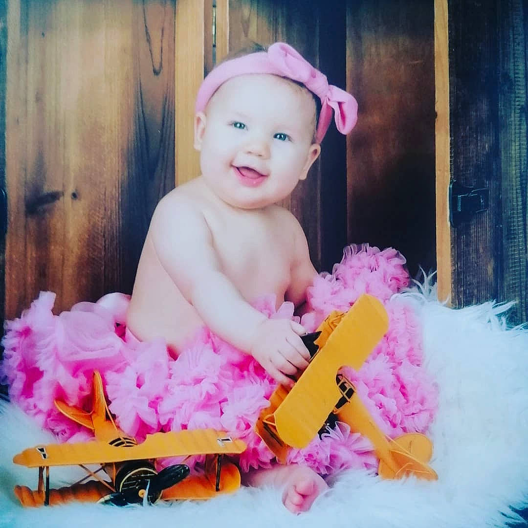 Giulia a rejoint le concours — aidez-le/la à gagner de superbes lots ! baby, baby_playing_with_toys, baby_products, baby_toddler_clothing, ballet_tutu, child, costume, costume_accessory, event, facial_expression, fun, happy, headpiece, magenta, party_supply, person, pink, sitting, smile, sweetness