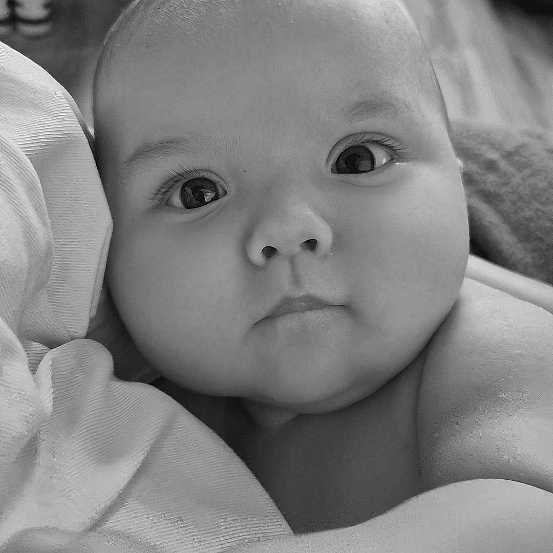 Maël a rejoint le concours — aidez-le/la à gagner de superbes lots ! baby, black_and_white, blanket, child, close_up, cozy, cute, expression, eyes, face, hand, head, indoor, infant, newborn, person, portrait, skin, soft_texture, warm