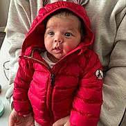 Alessyo participe au concours pour gagner de l'argent avec cette photo : baby, child, red_jacket, hood, ears, puffy_jacket, hands, adult, sweatshirt, beige_clothing, indoor, curious, wide_eyes, portrait, person, holding, seated, warm_clothing, cute, infant
