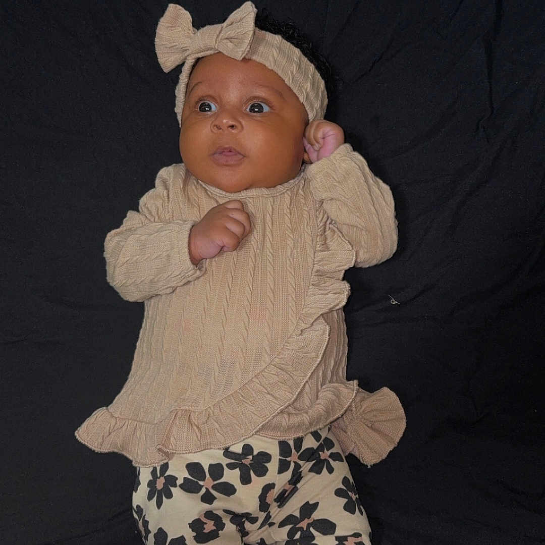 Keshaunda Coe joined the competition — help win amazing prizes! baby, child, cozy, curious, cute, dark_background, fashion, floral_pants, headband, indoor, infant, infant_fashion, lying_down, patterned_clothing, portrait, small_hands, sock, soft_fabric, sweater, young_child