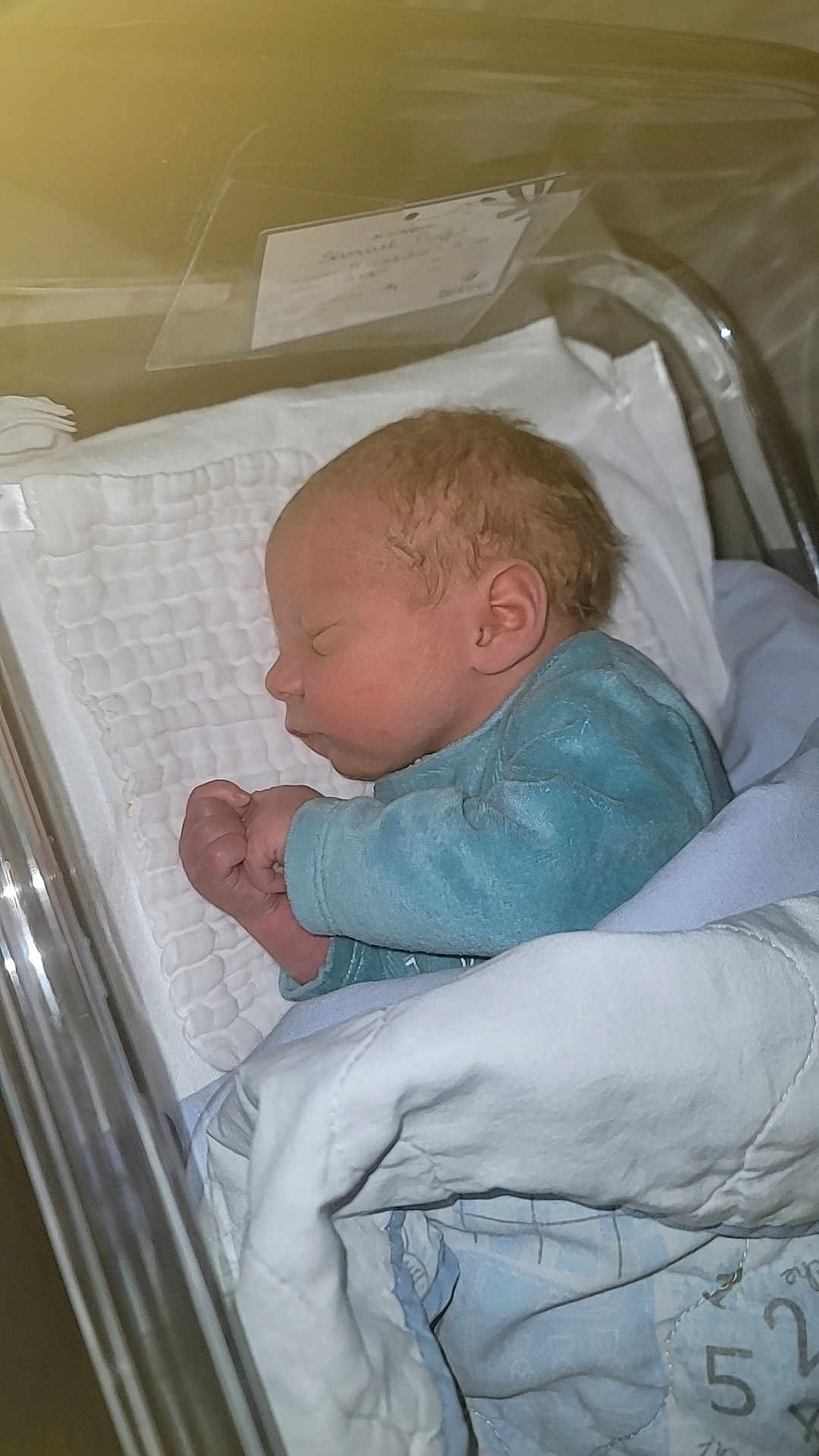 Samael participe au concours pour gagner de l'argent avec cette photo : newborn, baby, sleeping, hospital, bassinet, blanket, blue_clothing, infant, cute, peaceful, portrait, tiny_hands, wrapped, resting, soft, child, person, indoor, cozy, face