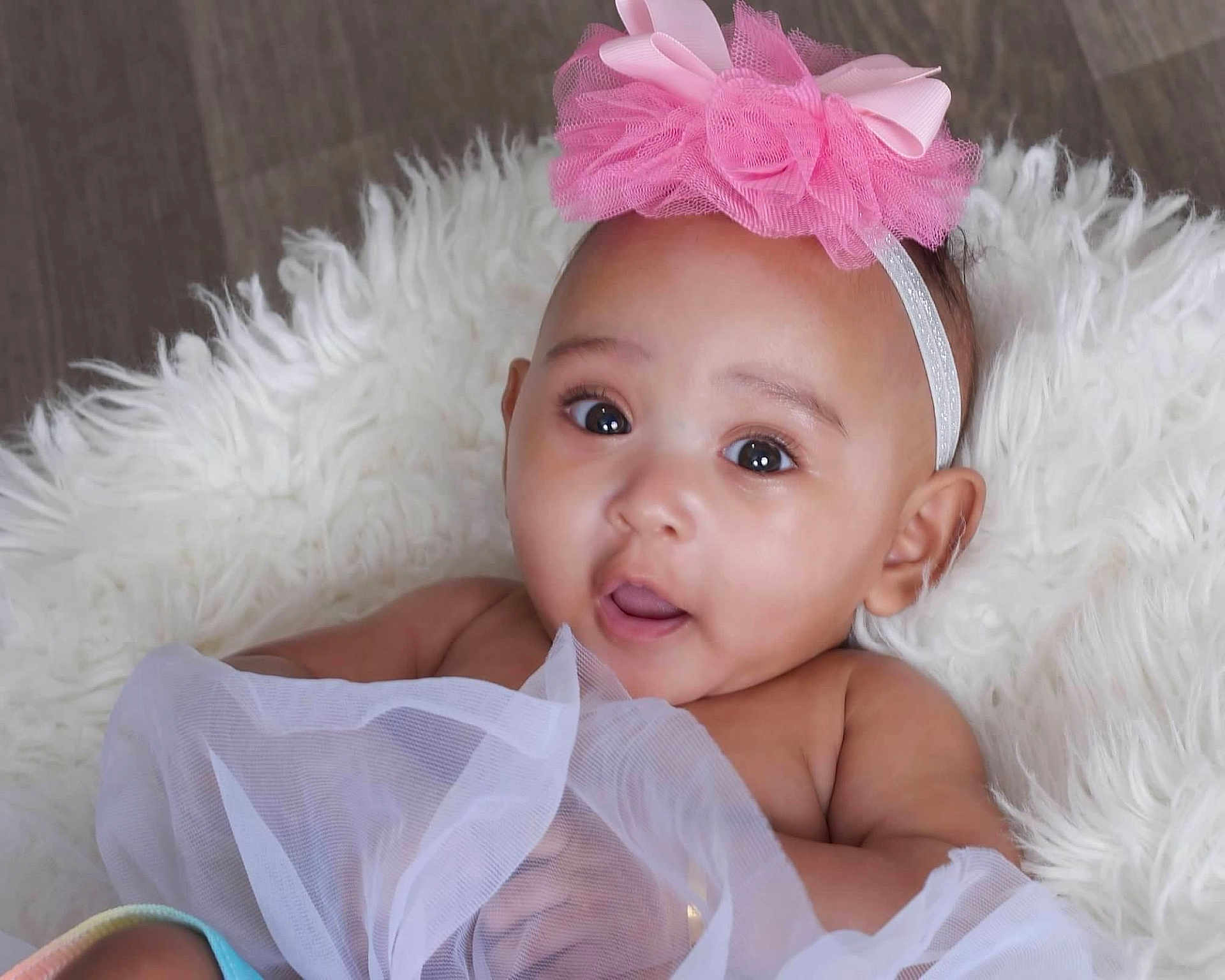 Xalori is registered to the contest to win money with this photo: baby, infant, child, headband, pink_bow, big_eyes, portrait, close_up, fluffy_rug, fur_rug, tulle, dress, bare_shoulders, adorable, cute, studio_photography, looking_up, open_mouth, soft_skin, ear