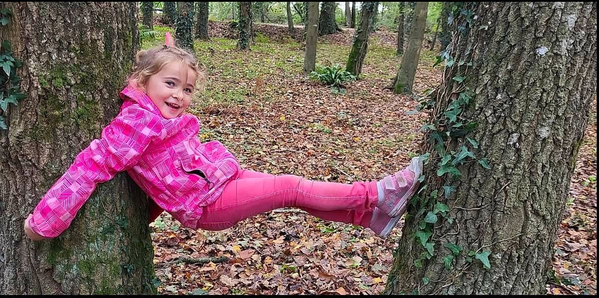 Maëlyne participe au concours pour gagner de l'argent avec cette photo : baby_toddler_clothing, biome, forest, grass, green, hand, happy, joy, leisure, natural_landscape, people_in_nature, person, plant, recreation, smile, terrestrial_plant, toddler, tree, trunk, wood