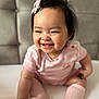 baby, candid, child, closeup, cute, face, hair_clip, happy, headwear, indoor, infant, person, pink_clothing, portrait, sitting, skin, smiling, socks, soft_surface, young_child
