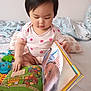 Freya joined the competition — help win amazing prizes! baby, bed, blanket, book, child, clothing, colorful, cute, early_learning, face, hand, indoors, pillow, playful, portrait, reading, sitting, soft_lighting, toddler, young_child
