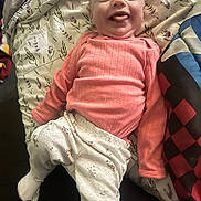 Paisleigh joined the competition — help win amazing prizes! baby, infant, smiling, tongue_out, pink_sweater, floral_pants, blanket, patterned_blanket, lying_down, happy, cute, child, indoors, cozy, fabric, soft_lighting, portrait, young_child, person, cheerful