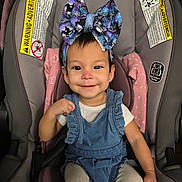 Evangeline joined the competition — help win amazing prizes! baby, child, car_seat, headband, bow, smile, happy, clothing, blue_dress, pink_blanket, earrings, face, rosy_cheeks, indoor, seatbelt, person, infant, cute, toddler, portrait
