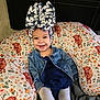Evangeline is registered to the contest to win money with this photo: baby, child, smiling, denim_jacket, headwear, bow, cushion, floral_pattern, cow_pattern, tights, sitting, indoor, happy, portrait, cute, clothing, person, face, infant, cozy