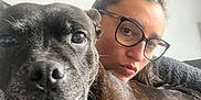 Iron a rejoint le concours — aidez-le/la à gagner de superbes lots ! woman, dog, glasses, face, pet, close_up, indoor, couch, black_dog, casual, portrait, human, animal, cozy, friendship, relaxed, furry, cute, companion, home