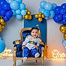baby, child, birthday, throne, balloons, blue, gold, party, celebration, smiling, happy, royal, costume, first_birthday, decorations, light, portrait, indoors, cute, festive