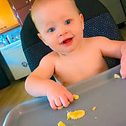 Killian joined the competition — help win amazing prizes! baby, high_chair, banana, food, kitchen, child, smiling, blue_eyes, indoor, person, feeding, cute, young_child, happy, hand, tray, furniture, home, eating, blond_hair
