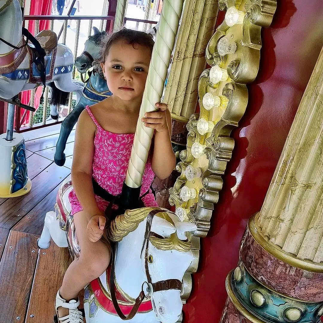 Lya participe au concours pour gagner de l'argent avec cette photo : amusementpark, carousel, child, clothing, face, female, footwear, fun, girl, head, pants, person, photography, play, portrait, sandal, shoe, sitting, tape, themepark