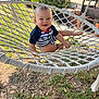 Liam a rejoint le concours — aidez-le/la à gagner de superbes lots ! toddler, child, hammock, outdoor, smiling, grass, garden, rope, sunlight, happy, baby, greenery, summer, playful, person, nature, casual_clothing, feet, daylight, relaxing