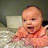 Alaira Beth is registered to the contest to win money with this photo: baby, infant, smiling, mouth_open, orange_clothing, blanket, bedroom, pillow, pattern, face, skin, hair, expression, cute, child, happy, indoors, portrait, newborn, human