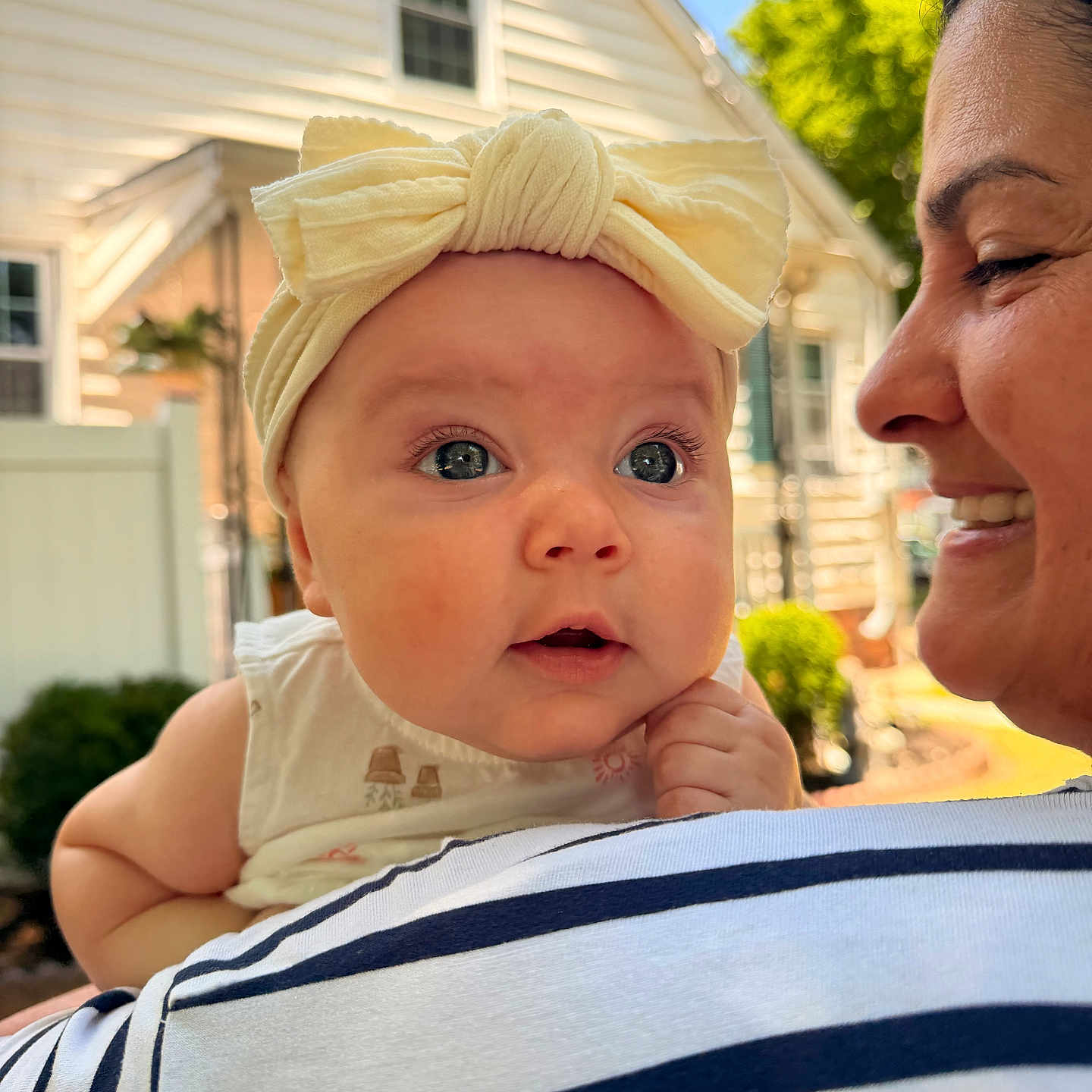 Alaira Beth is registered to the contest to win money with this photo: baby, child, woman, headband, bow, smile, face, outdoor, daylight, portrait, person, clothing, striped_shirt, house, window, greenery, garden, skin, closeup, holding