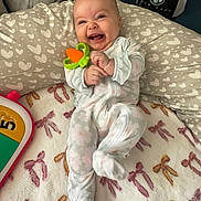 Alaira Beth joined the competition — help win amazing prizes! baby, infant, smiling, toy, onesie, pillow, heart_pattern, blanket, cap, indoor, cute, happy, child, face, person, soft_toys, playful, cozy, lying_down, comfortable