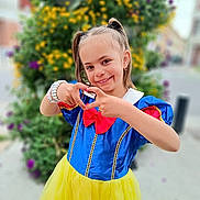 Elena participe au concours pour gagner de l'argent avec cette photo : child, girl, smile, costume, snow_white, dress, yellow_skirt, blue_top, red_bow, pigtails, bracelet, outdoor, flower, greenery, portrait, happy, gesture, cute, fashion, playful