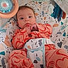 baby, infant, child, portrait, lying_down, bouncer, baby_seat, toy, playmat, patterned, pink_clothing, onesie, wide_eyed, hands, face, indoor, nursery, colorful, seated, photography