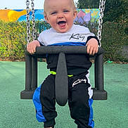 Jayden joined the competition — help win amazing prizes! toddler, child, swing, playground, smiling, happy, outdoor, clothing, socks, bear, chains, greenery, fence, colorful, mural, sky, daylight, fun, person, park
