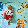 Selena is registered to the contest to win money with this photo: baby, blanket, child, clothing, colorful, cute, fish, fun, happy, indoor, infant, lying_down, numbers, playful, red_stripes, smiling, soft_texture, stars_pattern, turtle, underwater_theme