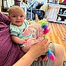 Selena joined the competition — help win amazing prizes! adult, baby, child, clothing, face, flooring, furniture, hand, happy, holding, indoor, living_room, person, plush_toy, rainbow, smiling, stroller, television, toy, unicorn