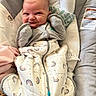 baby, infant, smile, face, clothing, blanket, sleeping_bag, cushion, baby_seat, indoor, cute, child, cozy, pattern, rainbow, zipper, apparel, person, newborn, happy