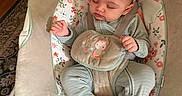 Selena is registered to the contest to win money with this photo: baby, baby_rocker, child, comfort, cute, fabric, face, feet, floral_pattern, hands, head_support, indoor, infant, nap, pajamas, peaceful, resting, seat, sleeping, young_child
