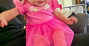 Selena is registered to the contest to win money with this photo: arms, baby, blur, cabinet, child, couch, decor, furniture, home, indoors, infant, legs, living_room, motion, person, pink_dress, seated, smile, sofa, toy