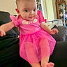 Selena is registered to the contest to win money with this photo: baby, pink_dress, infant, person, child, living_room, furniture, sofa, couch, blur, motion, legs, arms, smile, indoors, home, decor, cabinet, toy, seated