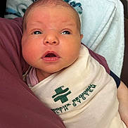 Sunnie joined the competition — help win amazing prizes! newborn, baby, infant, wrapped, blanket, hospital, health_system, face, eyes, mouth, skin, head, person, human, closeup, indoors, curious, lying_down, swaddled, soft