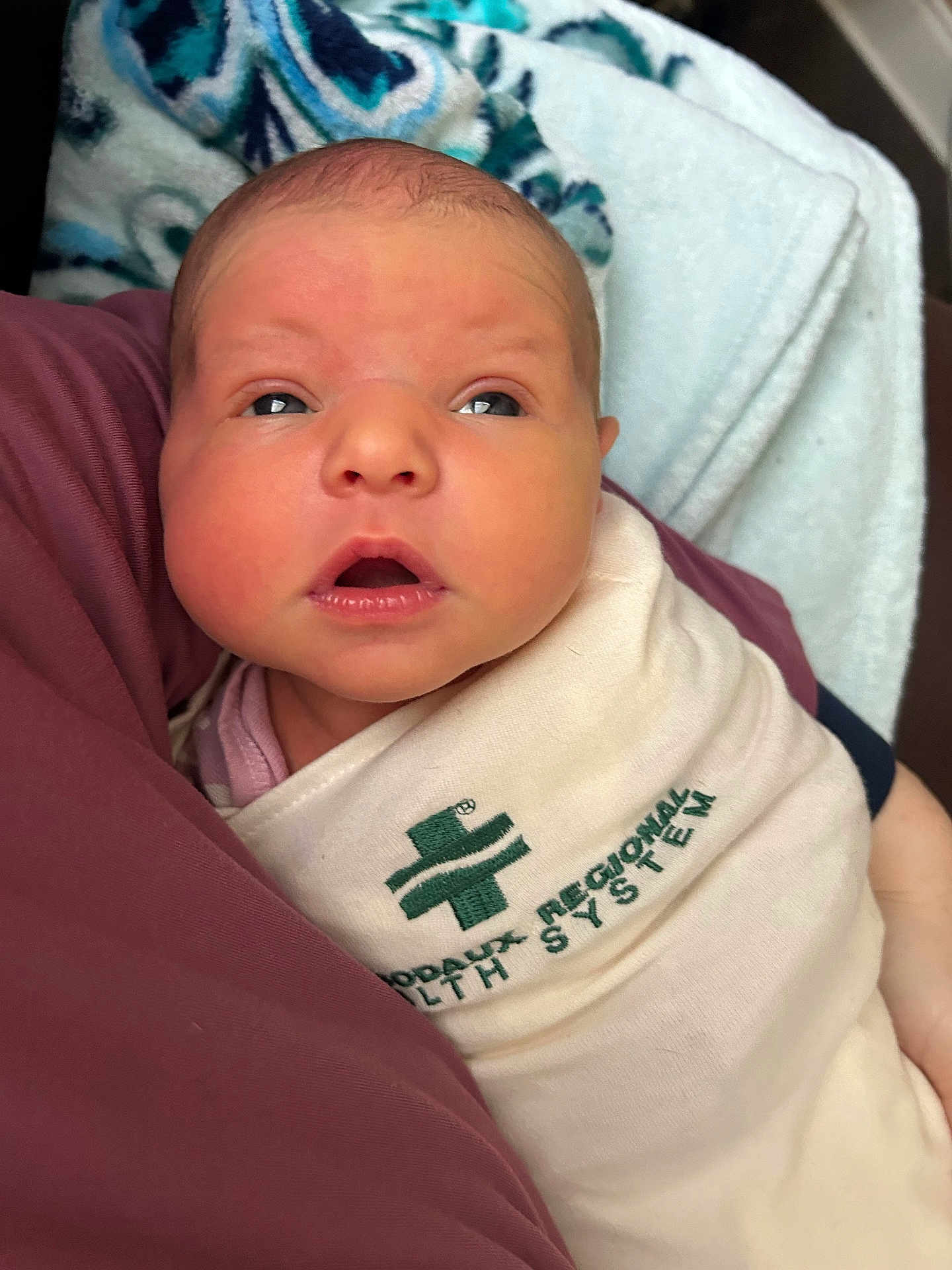 Sunnie joined the competition — help win amazing prizes! newborn, baby, infant, wrapped, blanket, hospital, health_system, face, eyes, mouth, skin, head, person, human, closeup, indoors, curious, lying_down, swaddled, soft