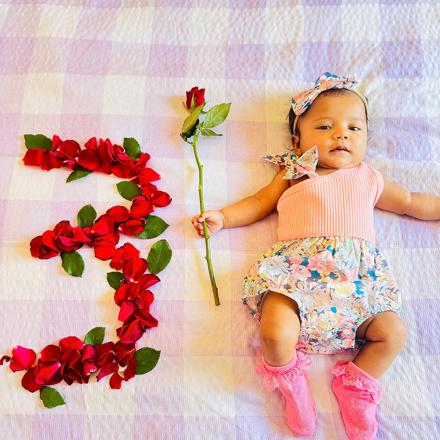 Sanvika joined the competition — help win amazing prizes! baby, blanket, celebration, child, cute, floral_dress, flower, headband, indoor, infant, lying_down, number_three, pastel_colors, person, pink_socks, portrait, red_rose, rose, rose_petals, soft_texture