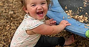 Raelynn joined the competition — help win amazing prizes! toddler, child, smiling, laughing, outdoor, playground, trampoline, wood_chips, sitting, barefoot, ponytail, hair, face, portrait, summer, play, happy, clothing, black_pants, colorful