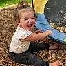barefoot, black_pants, child, daylight, face, happy, laughing, laughter, outdoor, patterned_shirt, play, playground, playground_equipment, ponytail, portrait, recreation, sitting, smiling, toddler, wood_chips