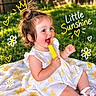 child, toddler, baby, smiling, laughing, eating, popsicle, dessert, outdoor, garden, grass, portrait, close_up, curly_hair, ponytail, dress, floral_pattern, blanket, sunlight, text_overlay