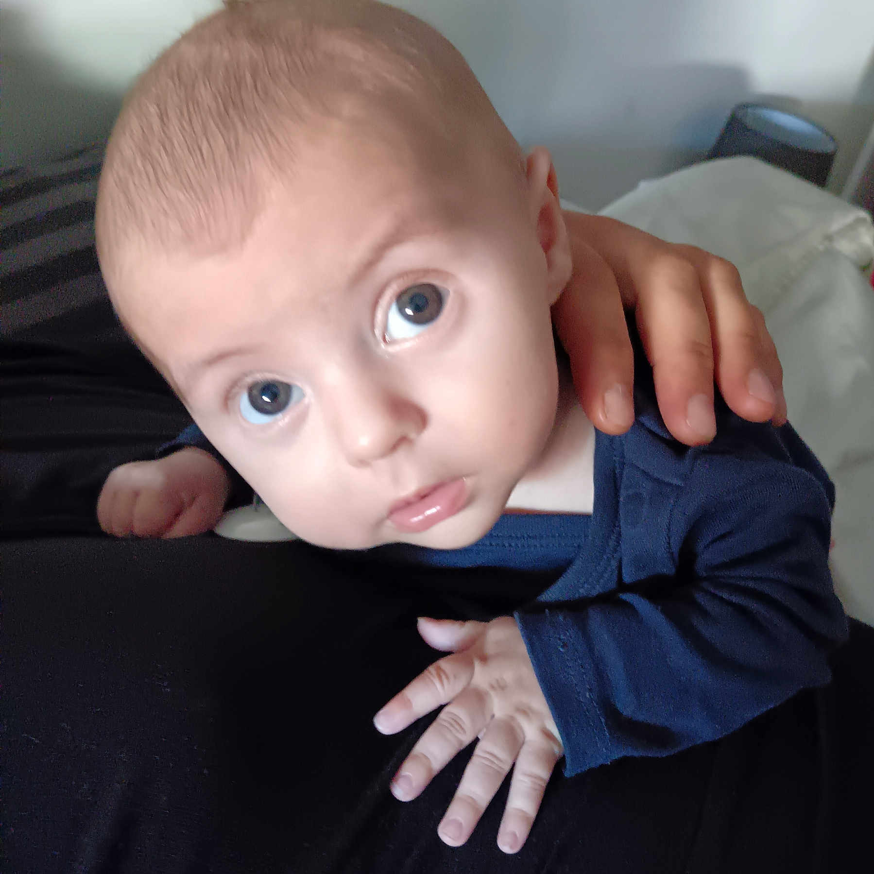 Enzo participe au concours pour gagner de l'argent avec cette photo : adult_hand, baby, blue_clothing, child, closeup, cute, expression, eyes, face, hand, holding, human, indoor, infant, looking, newborn, person, portrait, skin, soft_light