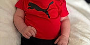 Jaxon joined the competition — help win amazing prizes! baby, smiling, infant, red_shirt, black_pants, puma_logo, soft_blanket, happy, cute, portrait, indoors, person, child, clothing, hand, face, head, sitting, skin, young