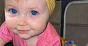 Amara joined the competition — help win amazing prizes! baby, child, infant, portrait, smiling, blue_eyes, yellow_bow, pink_clothing, headband, indoors, living_room, toys, playroom, furniture, couch, blanket, cartoon, paw_patrol, colorful, photography