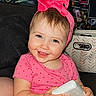 Amara is registered to the contest to win money with this photo: baby, child, infant, smiling, happy, portrait, pink, bow, headband, short_sleeves, polka_dots, sitting, toy, electronic_device, indoors, couch, cushion, colorful_background, baby_fashion, family_photo