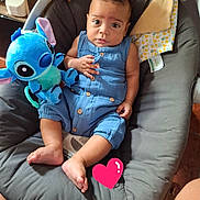 Maël participe au concours pour gagner de l'argent avec cette photo : child, baby, infant, blue_outfit, stitch_plush, plush_toy, stuffed_animal, bouncer, baby_seat, cushion, blanket, toy, barefoot, looking_at_camera, big_eyes, seated, indoor, human_face, brown_hair, soft_fabric