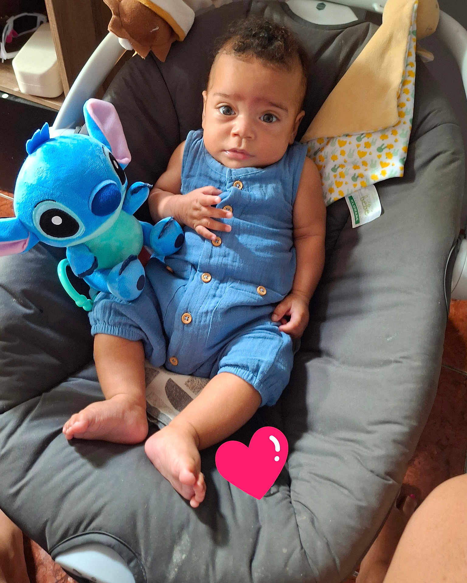 Maël participe au concours pour gagner de l'argent avec cette photo : child, baby, infant, blue_outfit, stitch_plush, plush_toy, stuffed_animal, bouncer, baby_seat, cushion, blanket, toy, barefoot, looking_at_camera, big_eyes, seated, indoor, human_face, brown_hair, soft_fabric