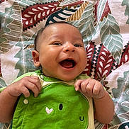 Nélyo participe au concours pour gagner de l'argent avec cette photo : baby, infant, smiling, green_clothing, onesie, dinosaur, happy, lying_down, blanket, patterned_blanket, cute, hand, face, child, indoors, portrait, expression, joy, small_child, human