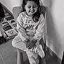 Lonie a rejoint le concours — aidez-le/la à gagner de superbes lots ! child, girl, smiling, sitting, chair, sneakers, clothing, long_hair, indoor, floor, toy_mat, alphabet_mat, happy, casual, crossed_legs, portrait, monochrome, wall, shadow, playful
