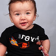 Lina a rejoint le concours — aidez-le/la à gagner de superbes lots ! baby, background, black_shirt, child, clothing, curly_hair, cute, eyebrows, face, hand, happy, indoor, infant, person, photography, portrait, sitting, skin, smiling, young