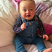 Kenza a rejoint le concours — aidez-le/la à gagner de superbes lots ! baby, bed, casual_clothing, child, cute, denim_overalls, face, floral_shirt, foot, hand, happy, head, indoors, infant, person, pillow, sitting, skin, smiling, young_child