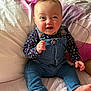 baby, bed, casual_clothing, child, cute, denim_overalls, face, floral_shirt, foot, hand, happy, head, indoors, infant, person, pillow, sitting, skin, smiling, young_child