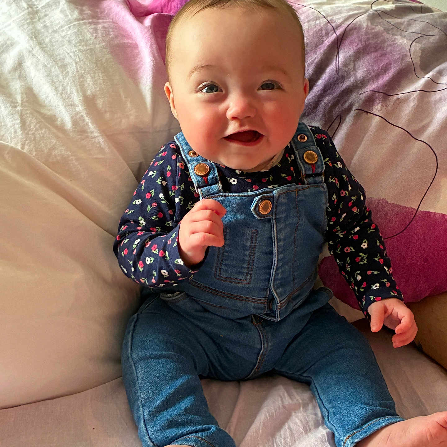 Kenza a rejoint le concours — aidez-le/la à gagner de superbes lots ! baby, bed, casual_clothing, child, cute, denim_overalls, face, floral_shirt, foot, hand, happy, head, indoors, infant, person, pillow, sitting, skin, smiling, young_child
