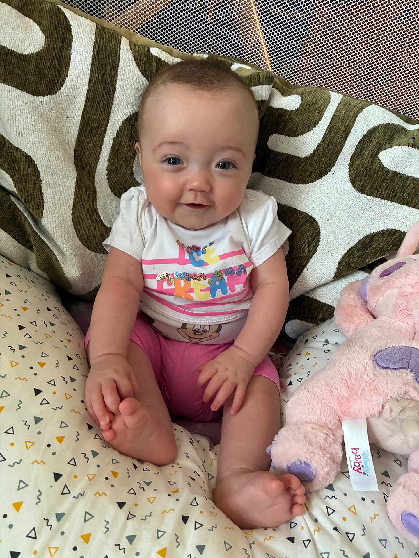Kenza participe au concours pour gagner de l'argent avec cette photo : baby, infant, smiling, sitting, pillow, plush_toy, clothing, pink_shorts, white_shirt, patterned_fabric, cute, happy, indoors, child, foot, hand, face, eyes, toy, comfort