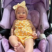 Olivia joined the competition — help win amazing prizes! baby, infant, smile, yellow_clothing, headband, bow, car_seat, purple, floral_pattern, cute, happy, child, person, sitting, indoors, foot, face, apparel, seat, comfort