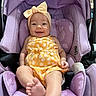 baby, infant, smile, yellow_clothing, headband, bow, car_seat, purple, floral_pattern, cute, happy, child, person, sitting, indoors, foot, face, apparel, seat, comfort